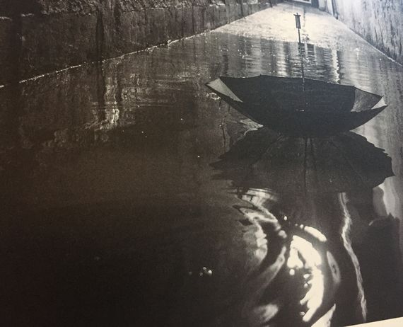 Kalostrape Ostatua, Jatetxea - Baiona Euskal Herria. Bar restaurant situé dans l'ancien cloitre des Visitandines, au coeur du Petit Bayonne. Concerts et soirées. Expositions du mois d'octobre 2017, avec Mathieu Prat. Photographie en noir et blanc, gros plan sur un parapluie flottant sur les inondations de Bayonne.